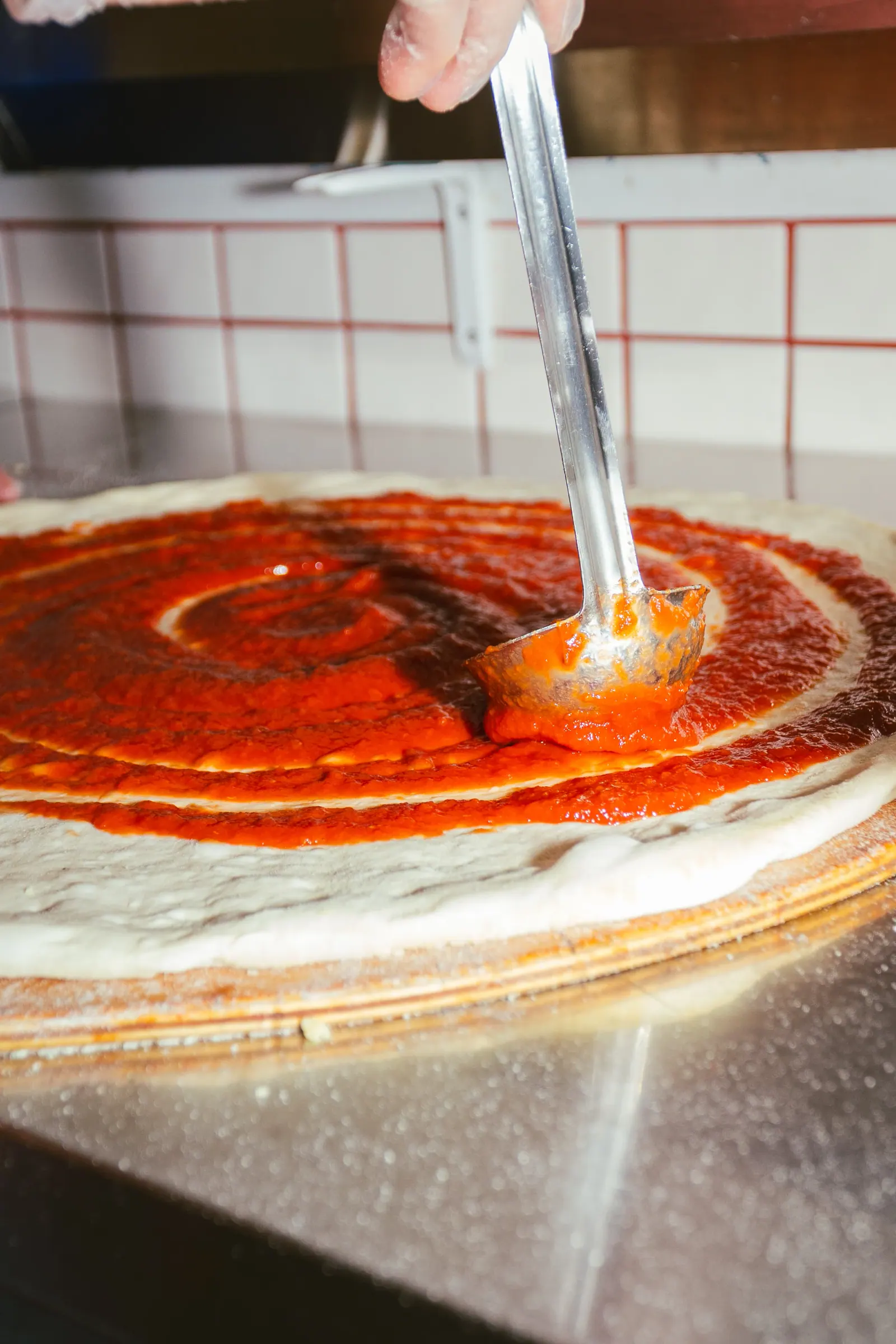 Prepping a pizza with sauce and cheese at Frankie's Cork