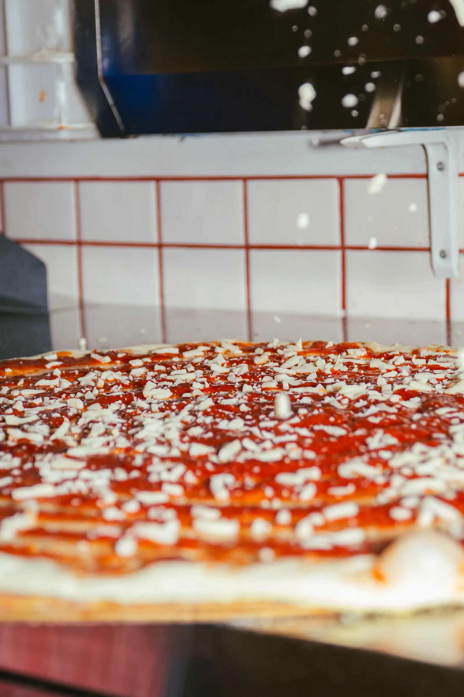Ladling tomato sauce onto pizza dough at Frankie's